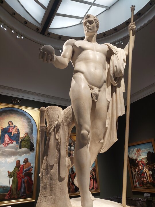 Napoleón como Marte pacificador Escultura de Canova representando a Napoleón con cara sosegada sujetando en una mano el globo terráquep y en la otra un bastón, y en general con un tono divino